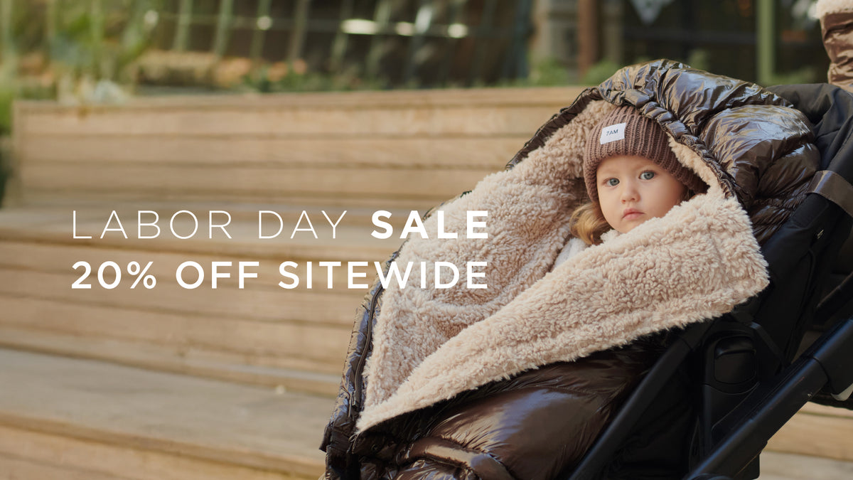 Image of a kid covered with a half open footmuff attached to the stroller, text overlay says "labor day sale 20% sitewide"