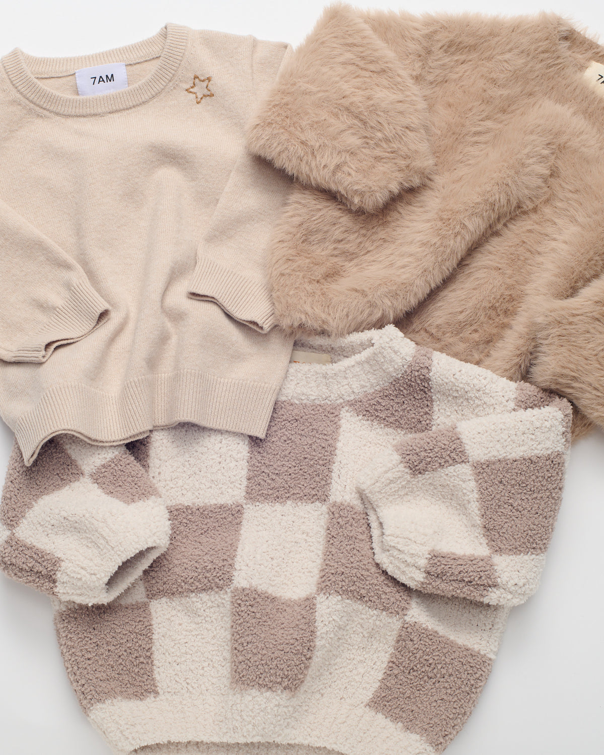 3 sweaters (oat faux cashmere, brown furry and checkered ecru and pecan sweater) layed flat.