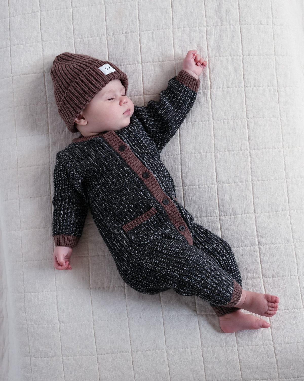 a baby is sleeping with a beanie and a jumpsuit