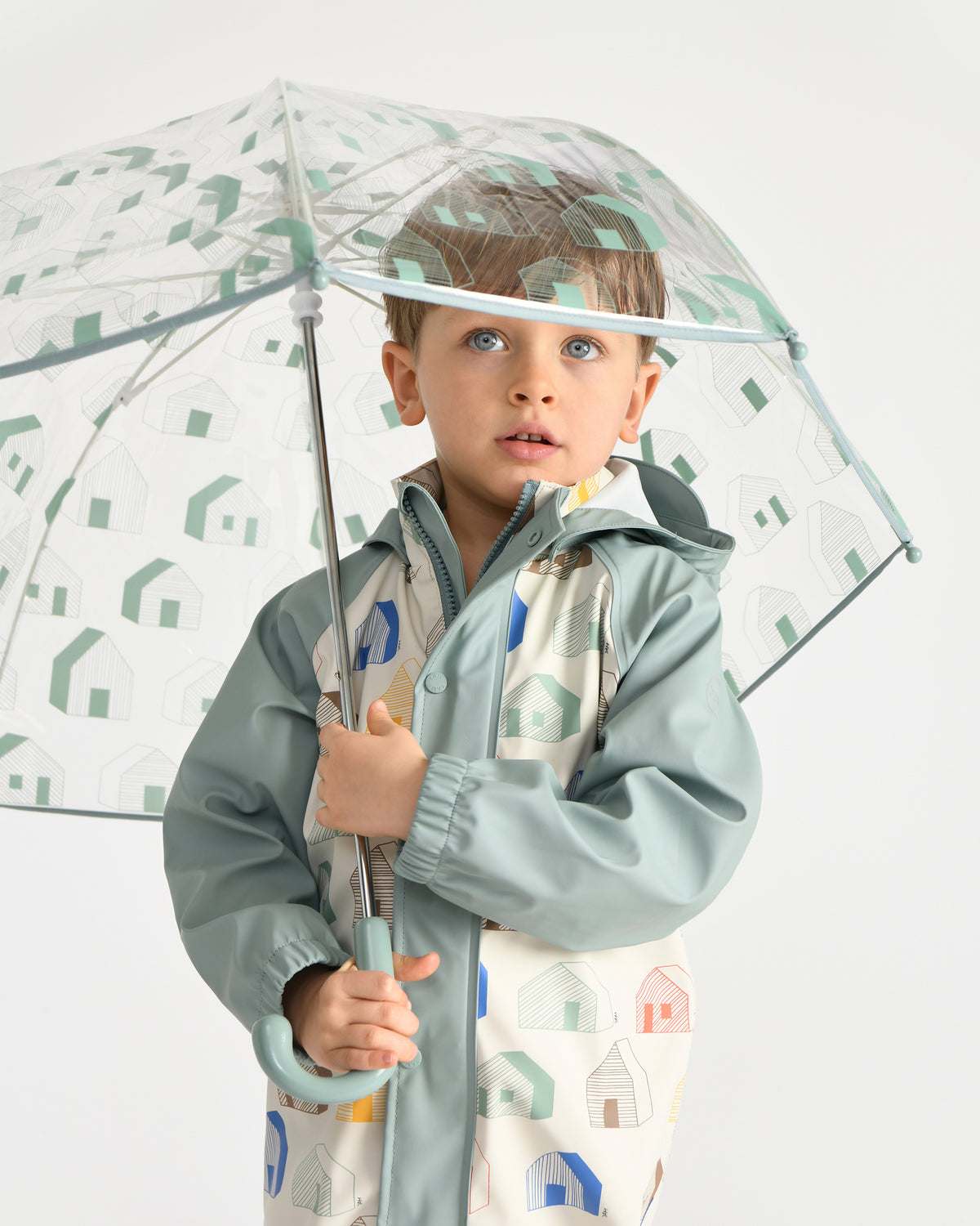 Child holding a transparent umbrella with geometric patterns on a white background